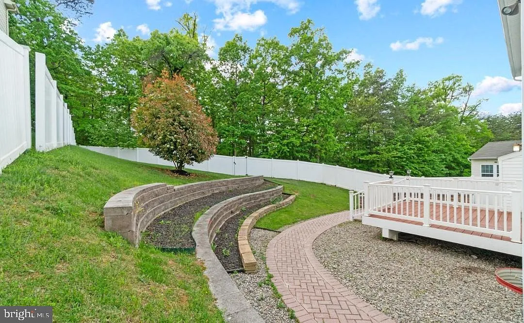 Tiered curved block retaining wall terraces along a sloped backyard in Elkridge, Maryland with a herringbone paver walkway